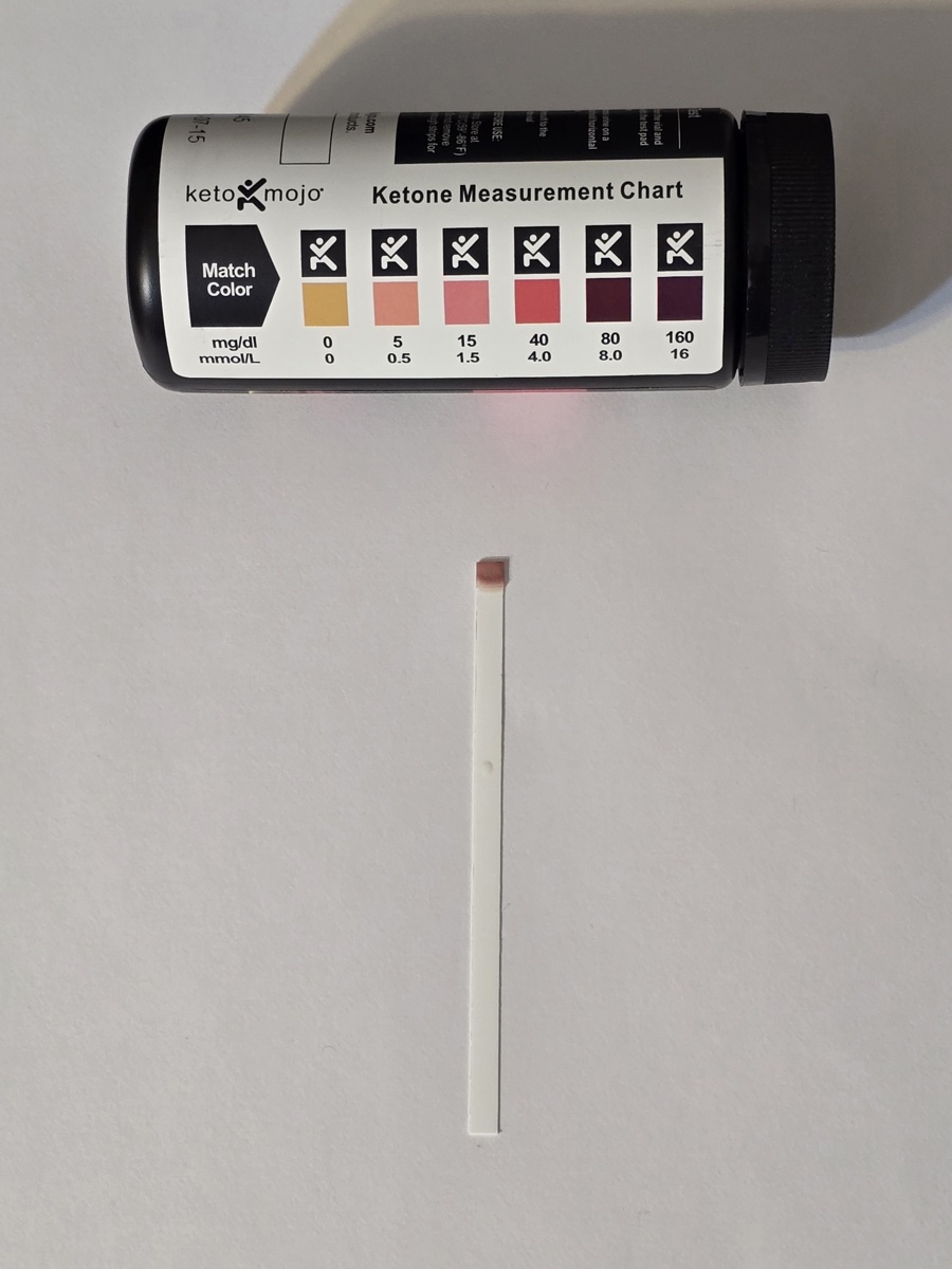 Keto Mojo ketone strip on day 7 next to the color chart